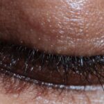 Mindfulness Beauty - Closeup of crop anonymous ethnic person with long eyelashes and shiny delicate skin in light ray