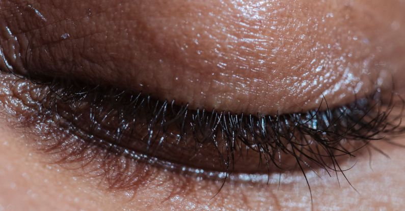 Mindfulness Beauty - Closeup of crop anonymous ethnic person with long eyelashes and shiny delicate skin in light ray