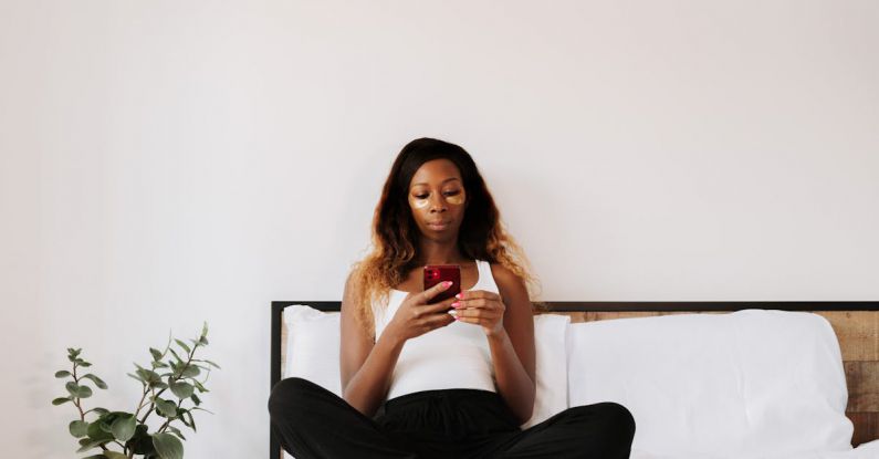 Cosmetic Technology - Woman using phone while sitting on bed